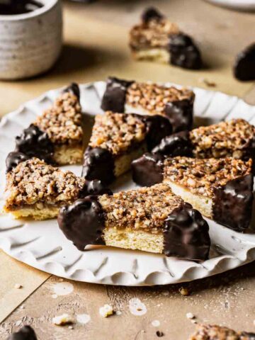 Nussecken bars dipped in chocolate on a white fluted plate.