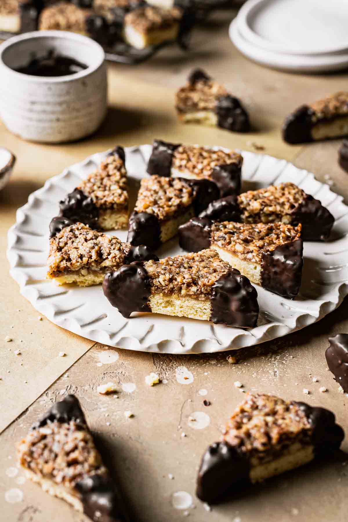 Nussecken bars dipped in chocolate on a white fluted plate.