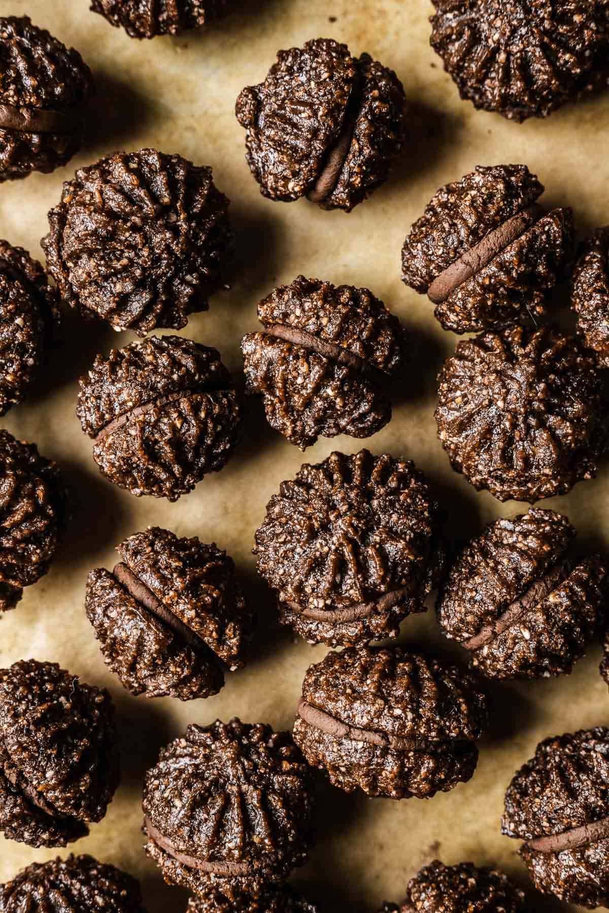 Ganache filled baci di Alassio sandwich cookies on a brown parchment lined baking sheet.