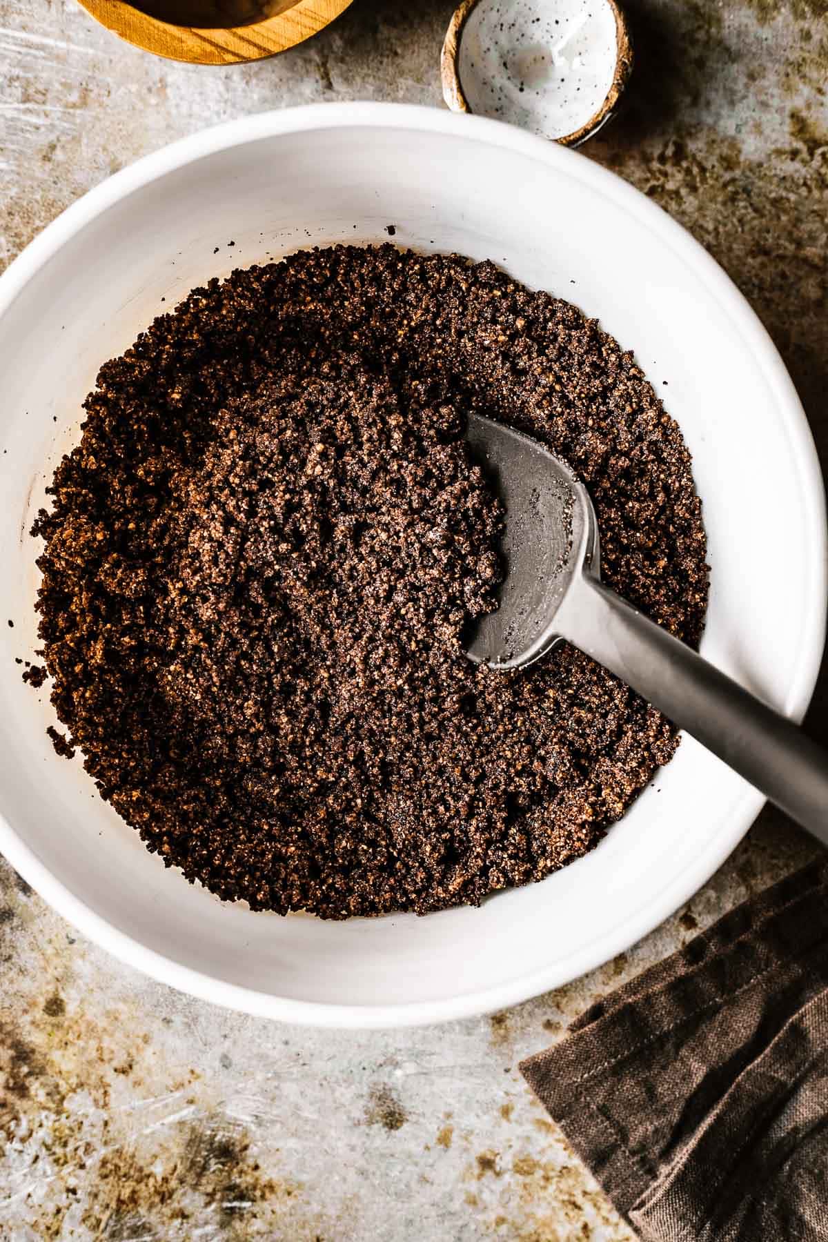 Ground hazelnuts and sugar mixed with cocoa powder and honey in a ceramic bowl.