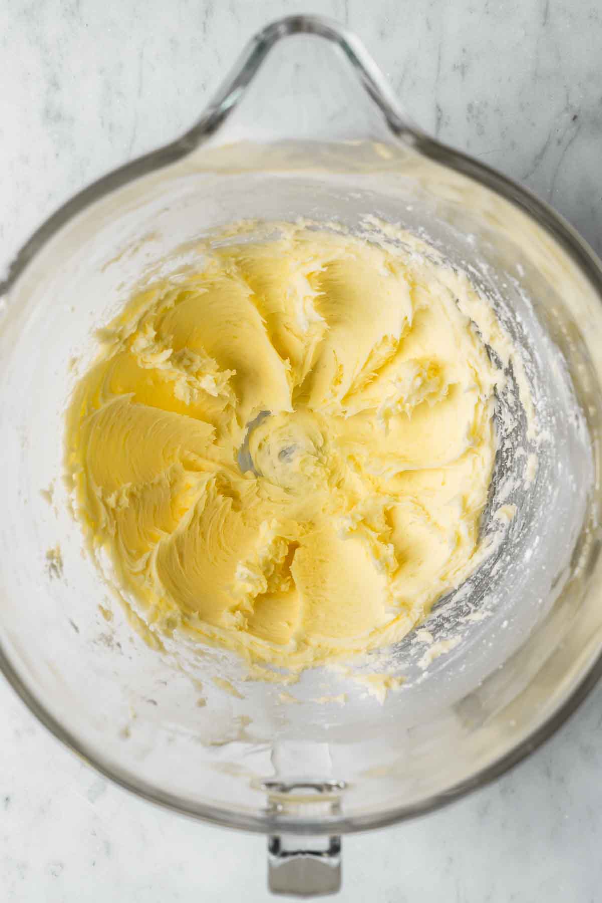 Creamed butter in a clear glass mixing bowl.