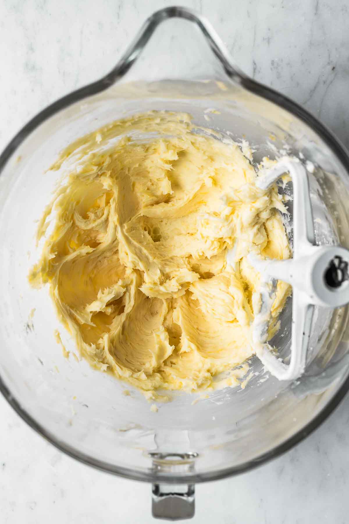 Butter, sugar, lemon oil and lemon zest mixed together in a glass mixing bowl.