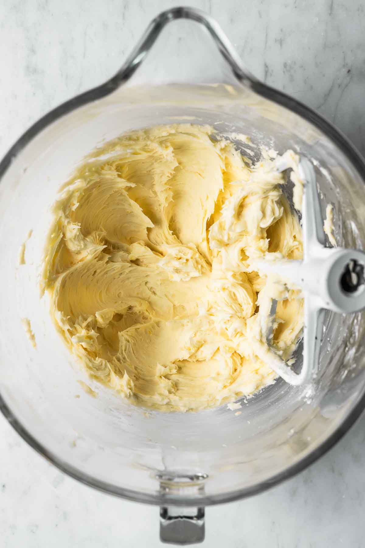 Creamed butter and sugar in a clear glass mixing bowl.