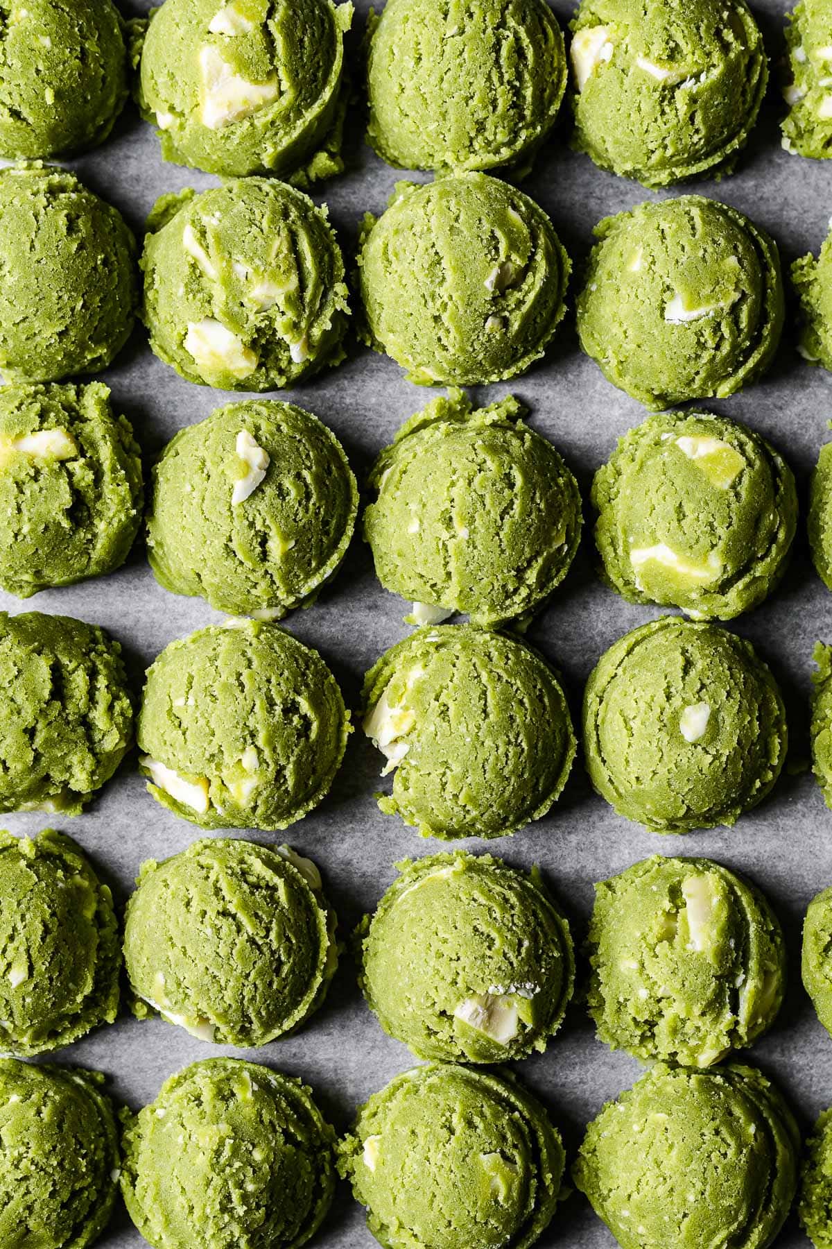 Scoops of vibrant green matcha chocolate chip cookie dough lined up in rows.