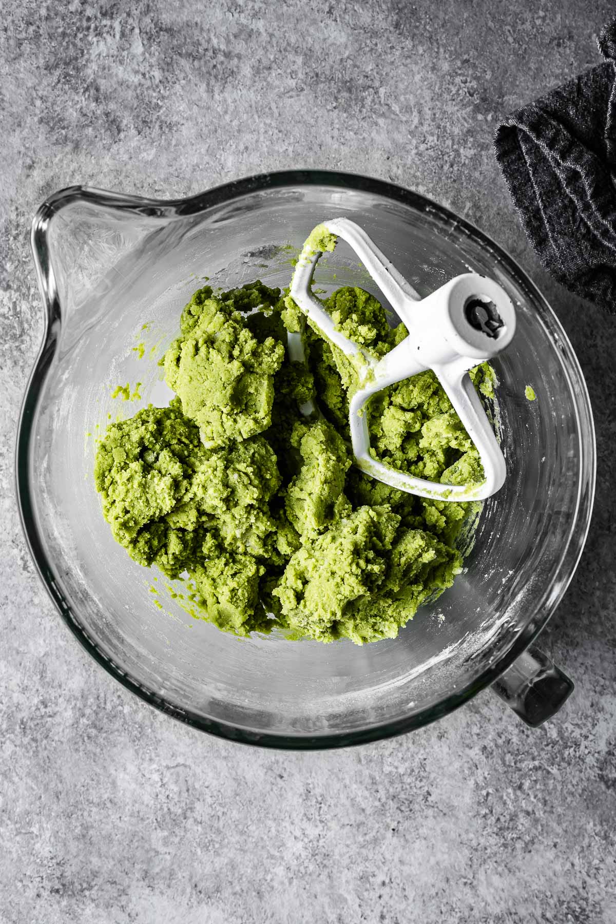 Green matcha cookie dough in a glass mixing bowl.