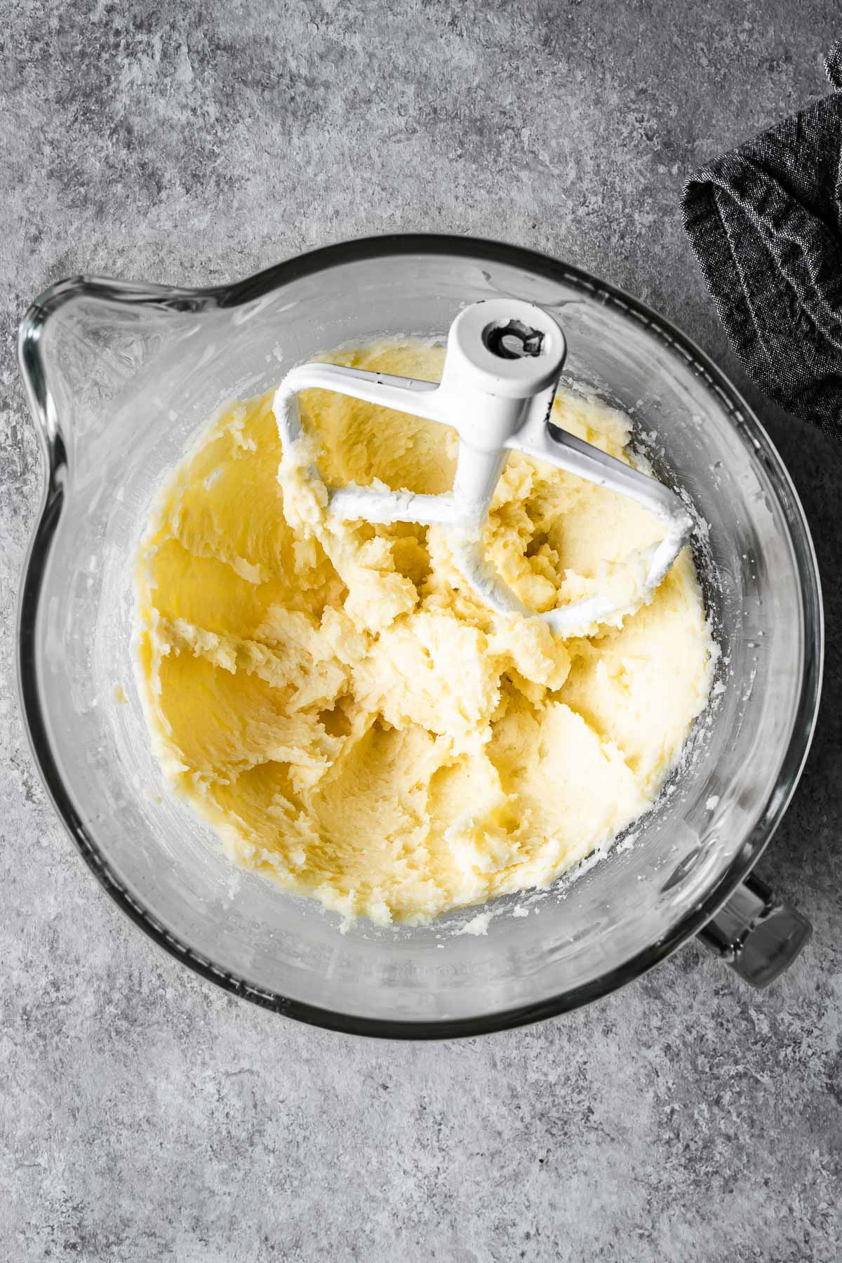 Creamed butter and sugar with eggs and vanilla in a glass mixing bowl.