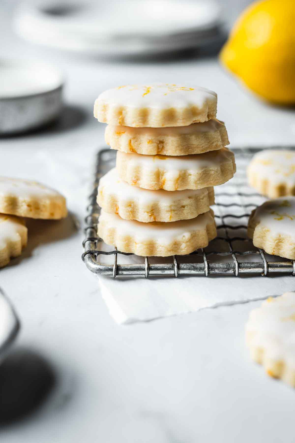 A stack of glazed lemon shortbread cookies on a cooling rack.