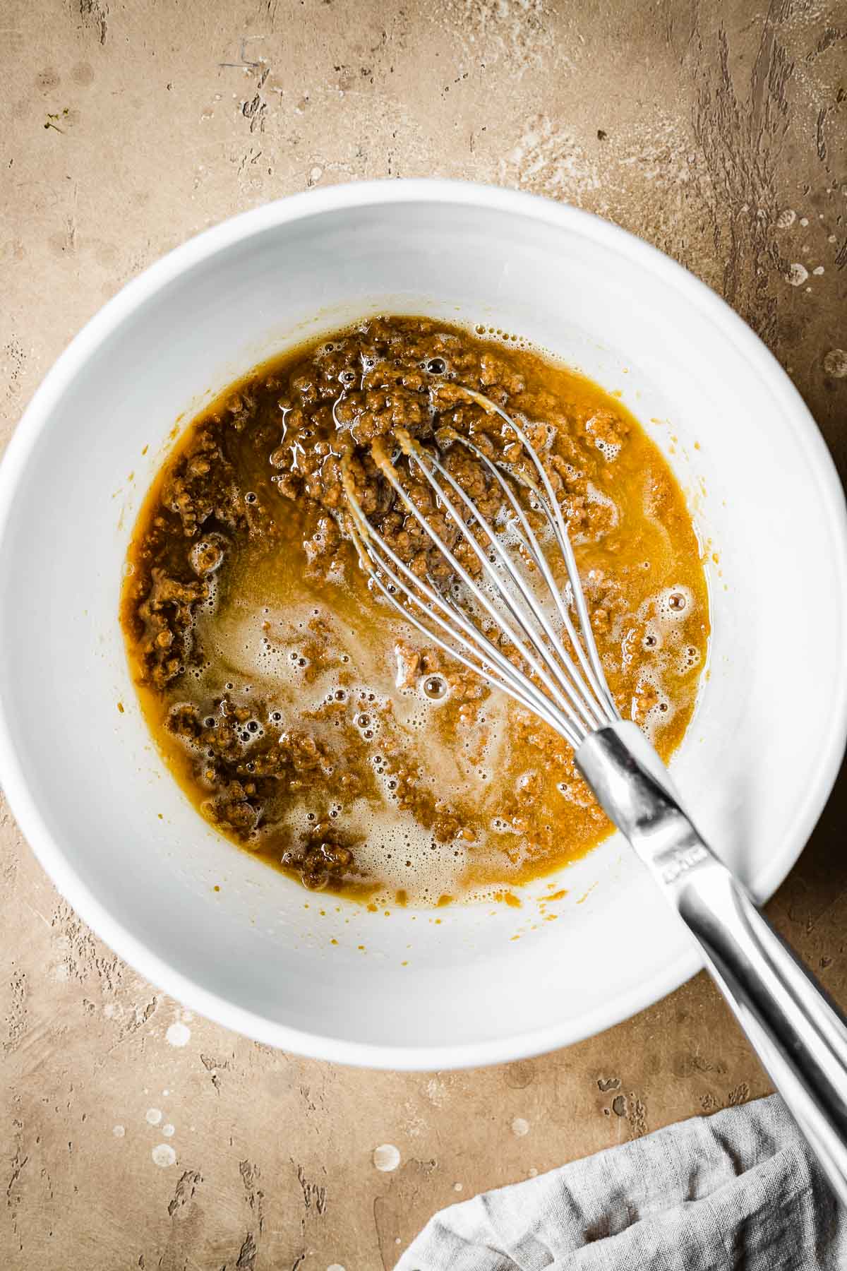 Melted butter, sugar and biscoff spread in a white ceramic mixing bowl.