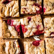 Raspberry white chocolate blondies on a wooden cutting board.