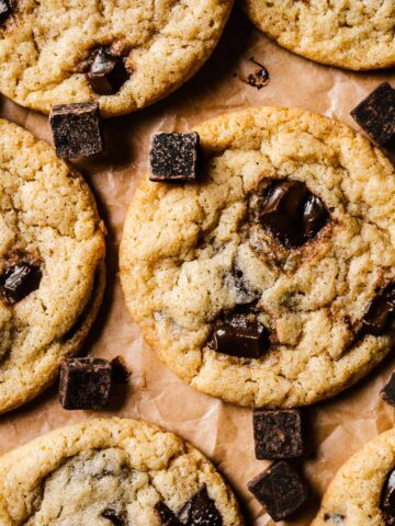 A close up image of egg free chocolate chip cookies on brown parchment paper.