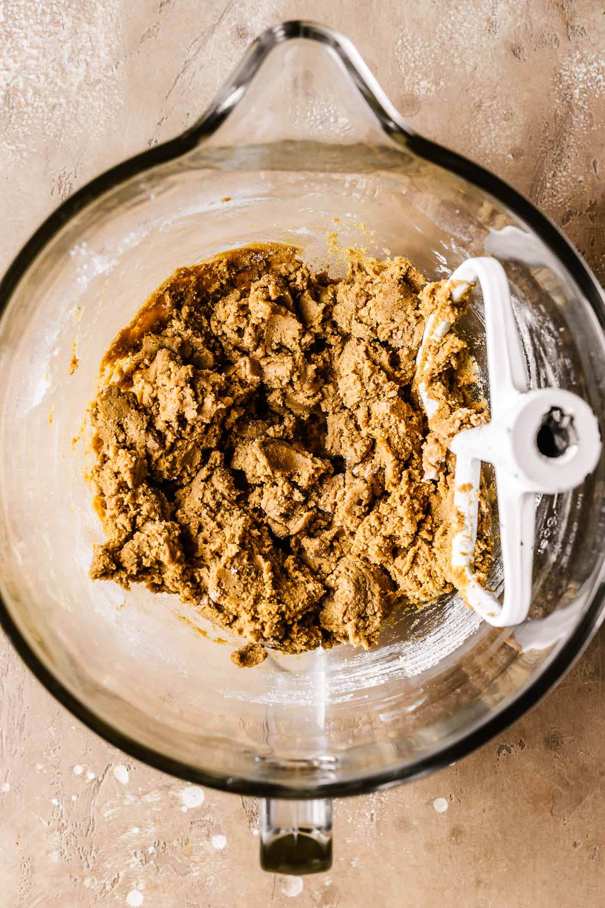 Dry ingredients for cookie dough added to wet ingredients in a glass mixing bowl.