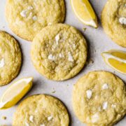 Lemon white chocolate cookies with lemon slices in between on white parchment paper.