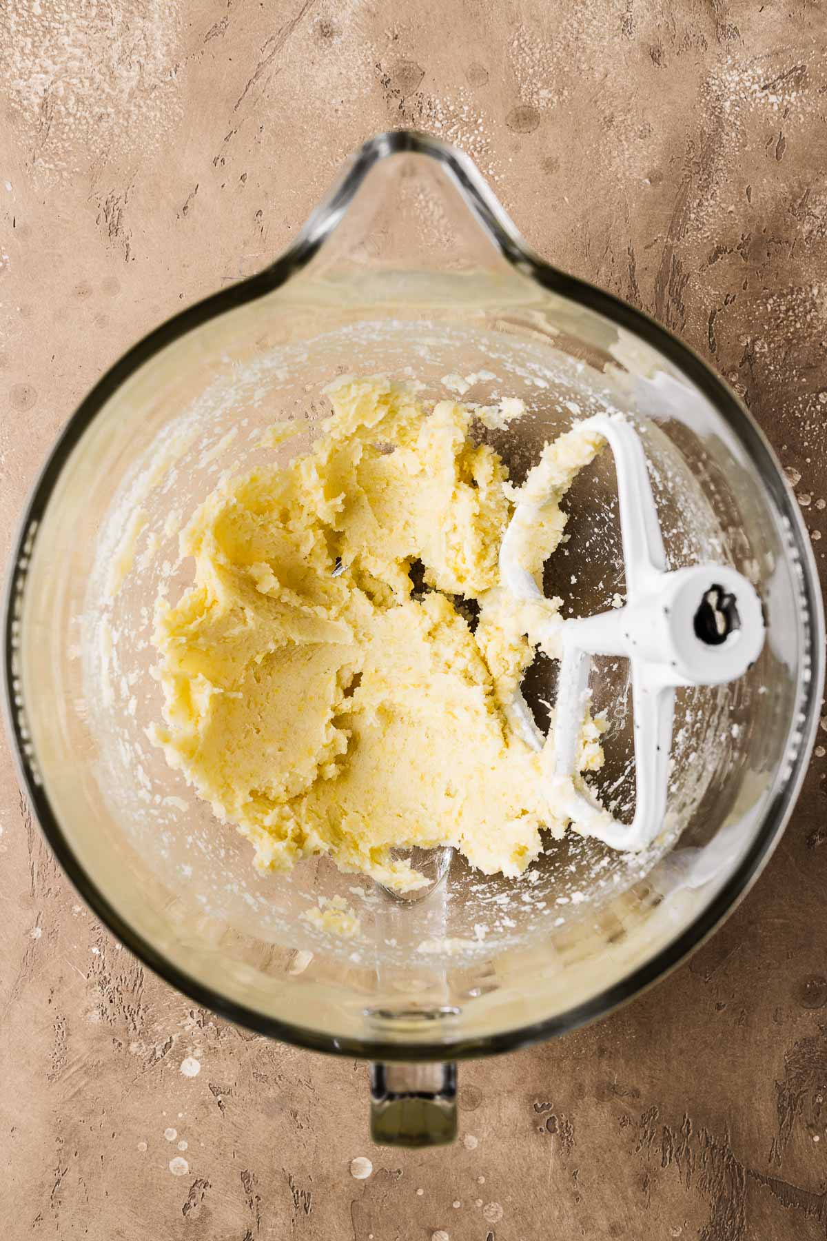 A clear glass mixing bowl with creamed butter and sugar.