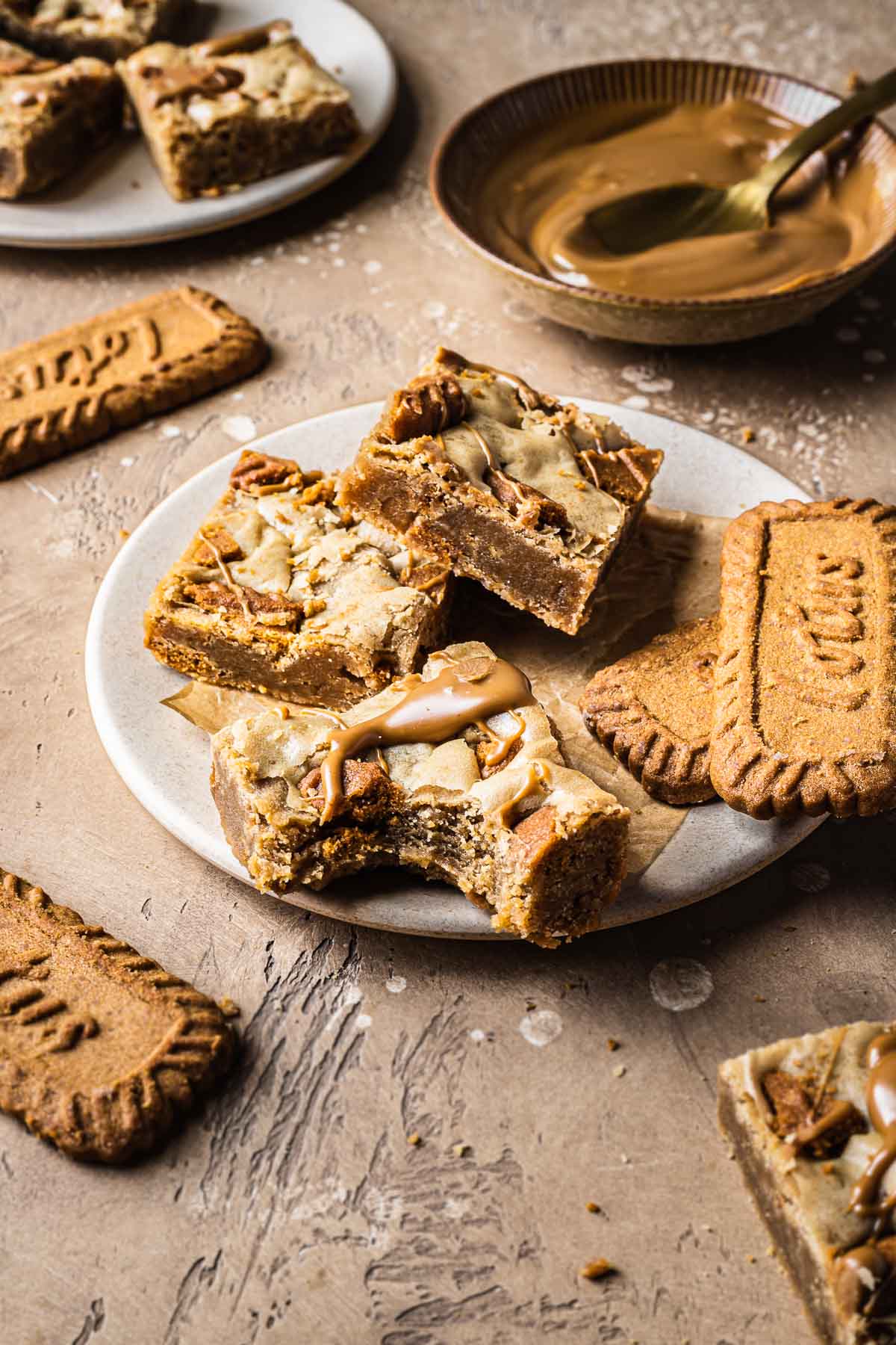 A stack of biscoff blondies on a plate showing the sliced interior.