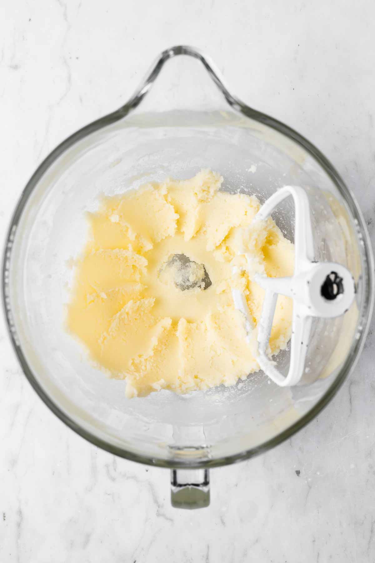 Creamed butter and sugar in a clear glass mixing bowl.