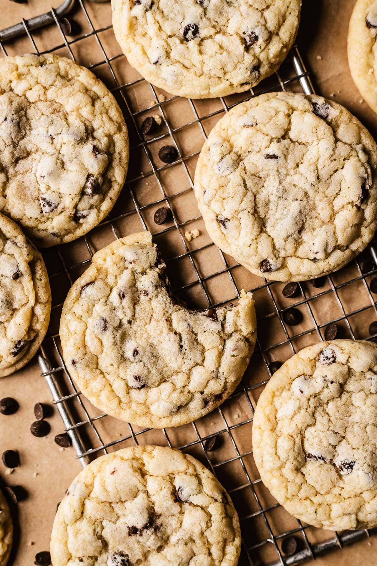 Chocolate chip cookies on a wire cooling rack with one bite taken out of a cookie.