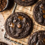 A closeup of dark brown cookies on a vintage cooling rack with brown parchment paper underneath.