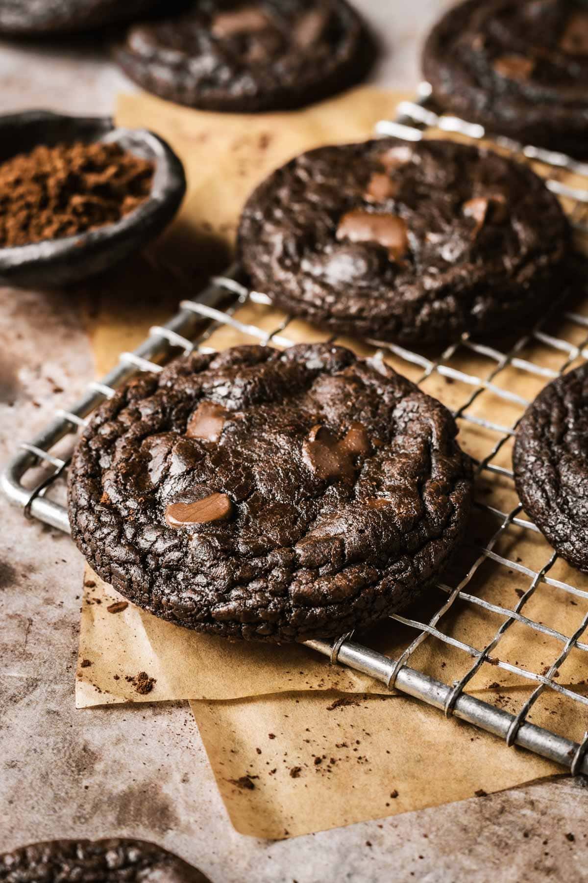 An angled photo of chocolate cookies on a vintage metal cooling rack.