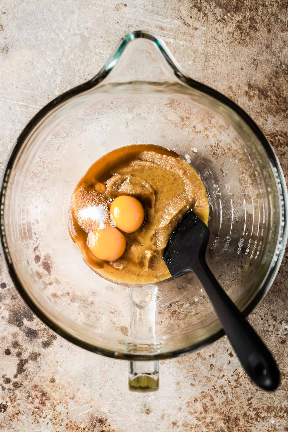 Eggs, vanilla and salt being mixed into butter and sugar in a bowl.