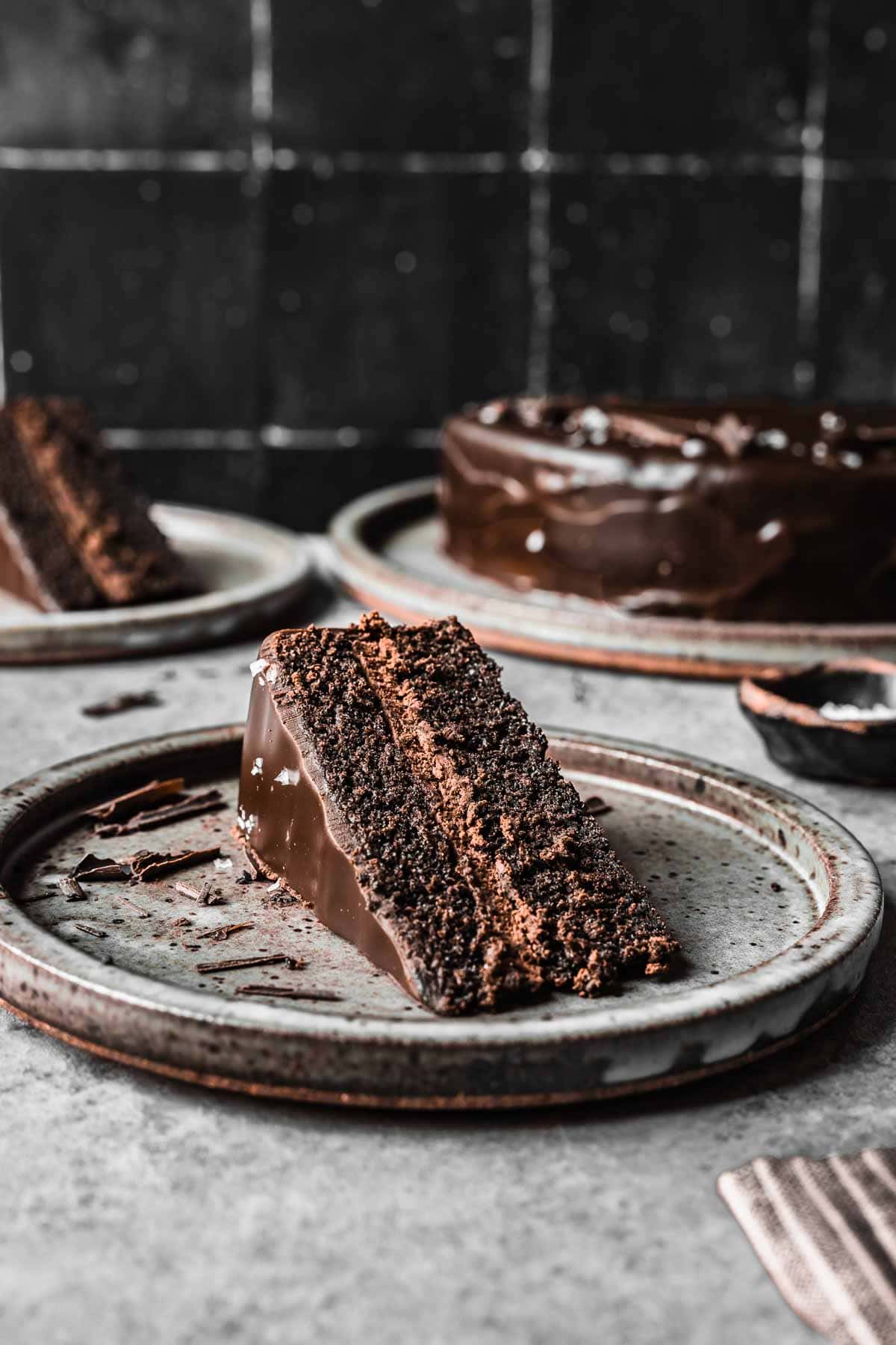 A slice of chocolate  ganache cake turned on its side on a plate.