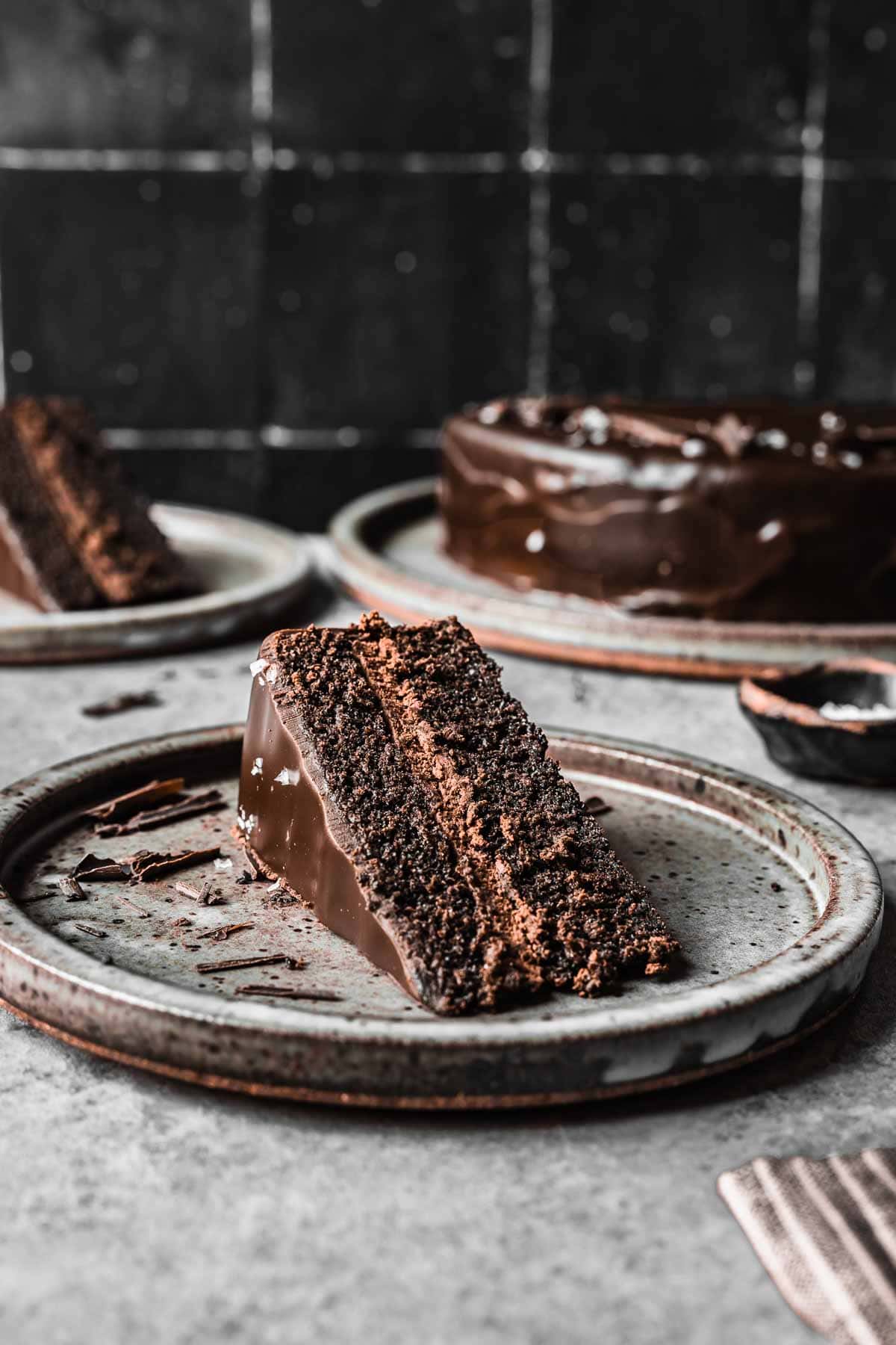 A slice of chocolate cake turned on its side on a grey ceramic plate.