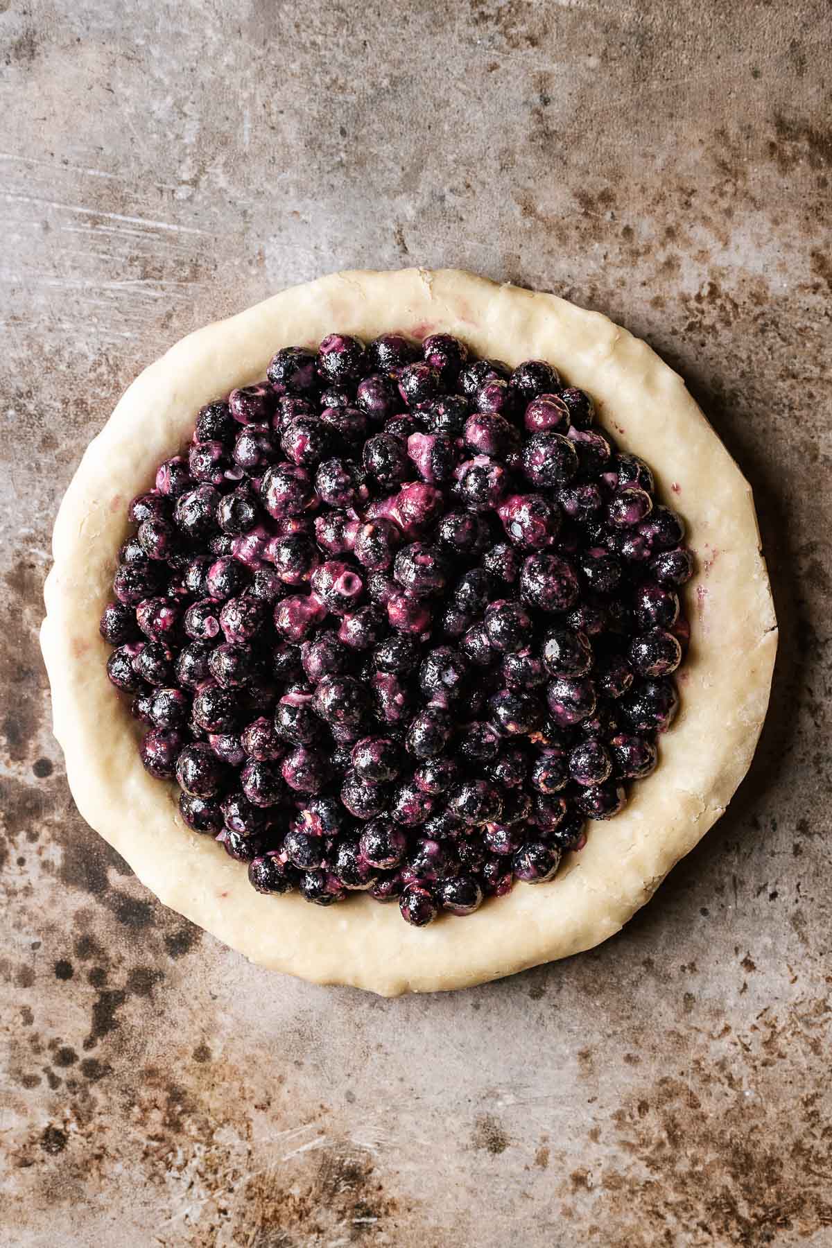 An unbaked bottom pie crust filled with frozen berries.