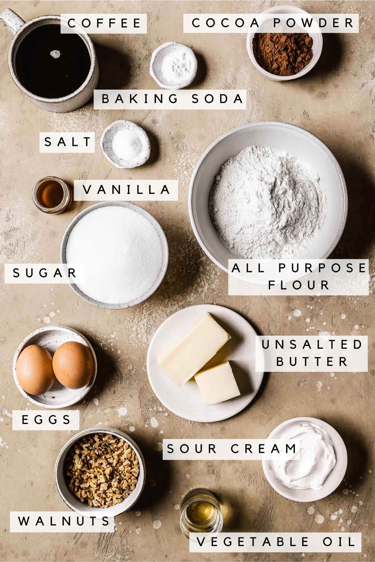 Labeled ingredients in bowls for a chocolate walnut cake.