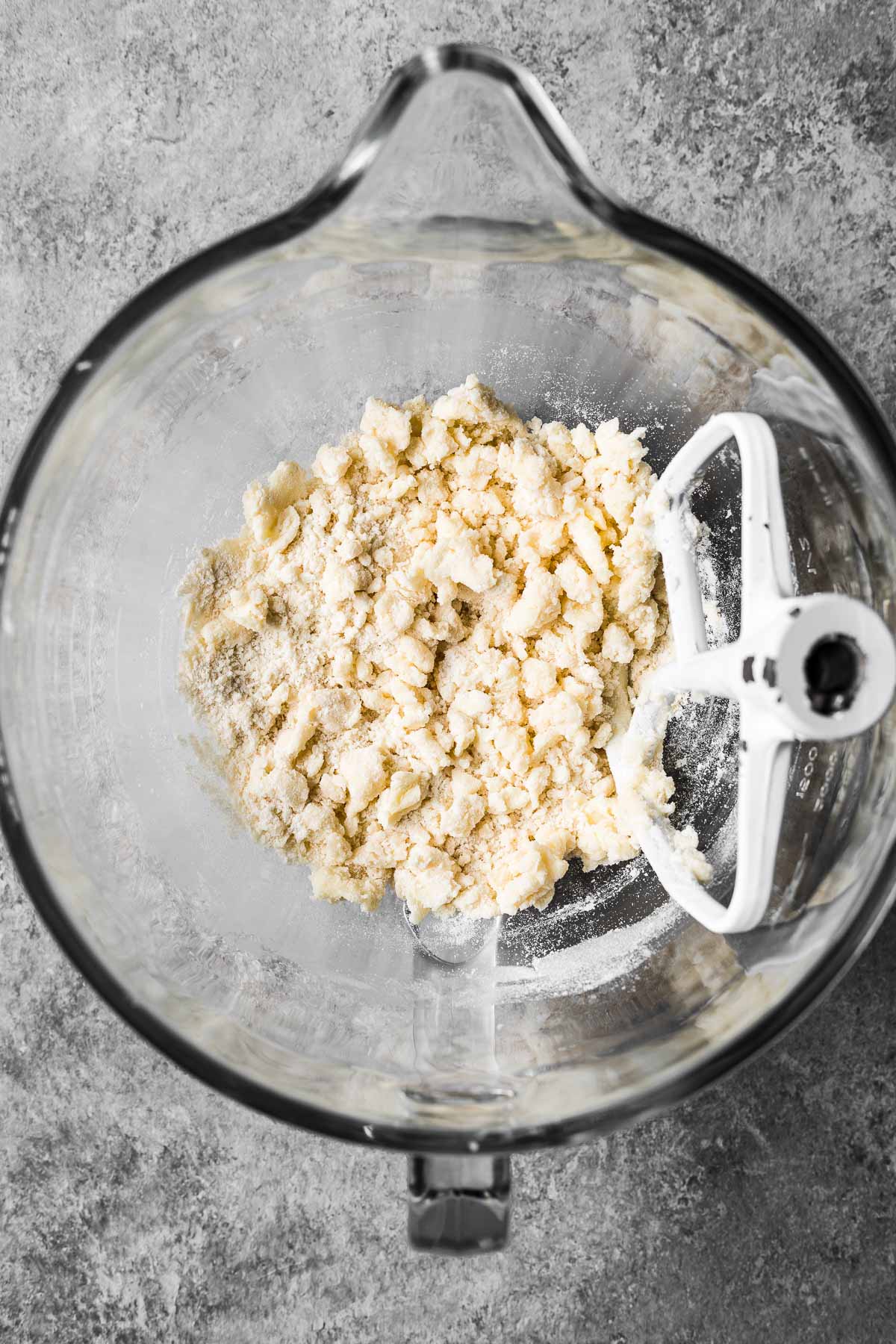 A glass mixing bowl with dry ingredients added to the butter and sugar.