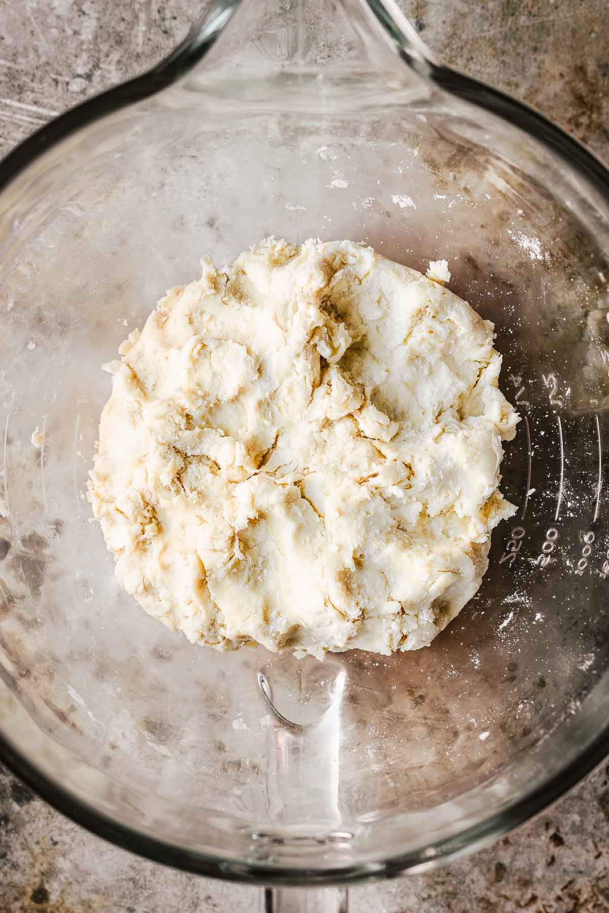 A glass mixing bowl with finished dough for cherry rhubarb pie crust.