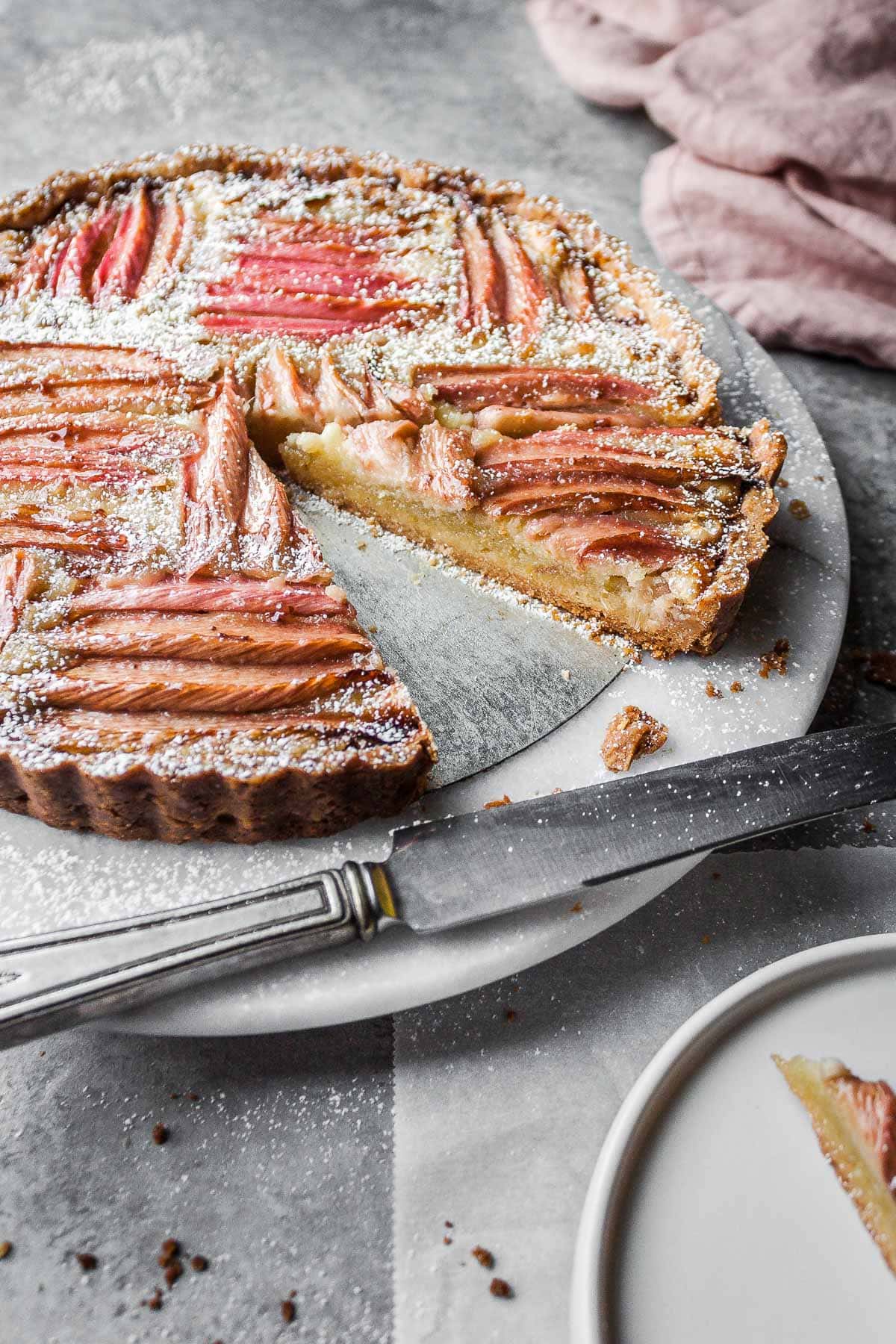 An angled view of a tart filled with almond cream and rhubarb.