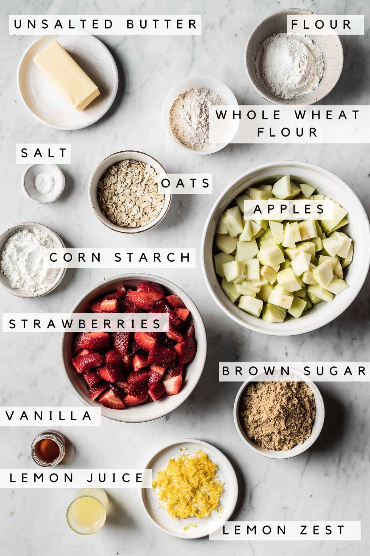 Labeled ingredients in bowls for a strawberry apple crisp recipe.