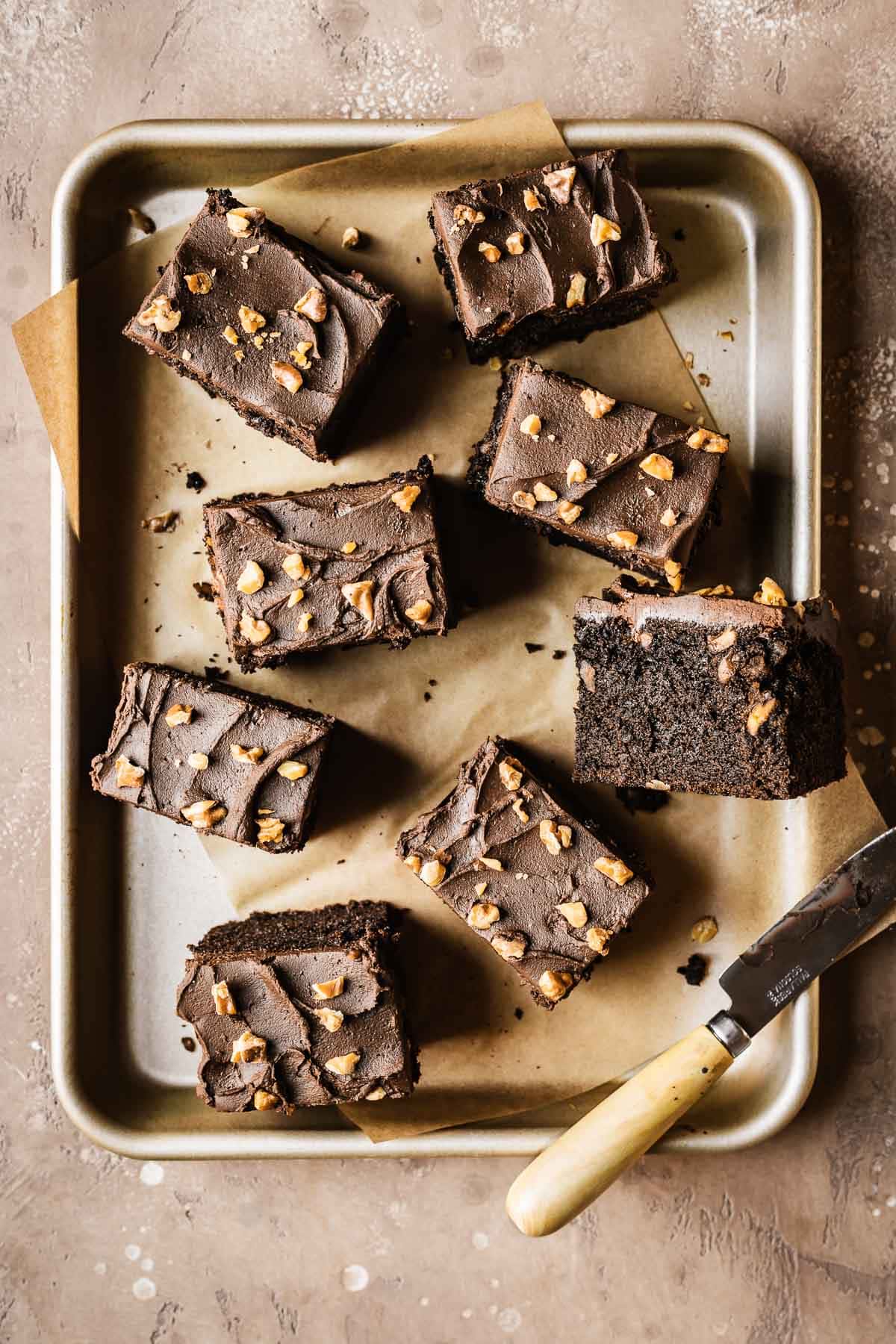 Slices of chocolate cake on a small gold baking pan lined with brown parchment paper.