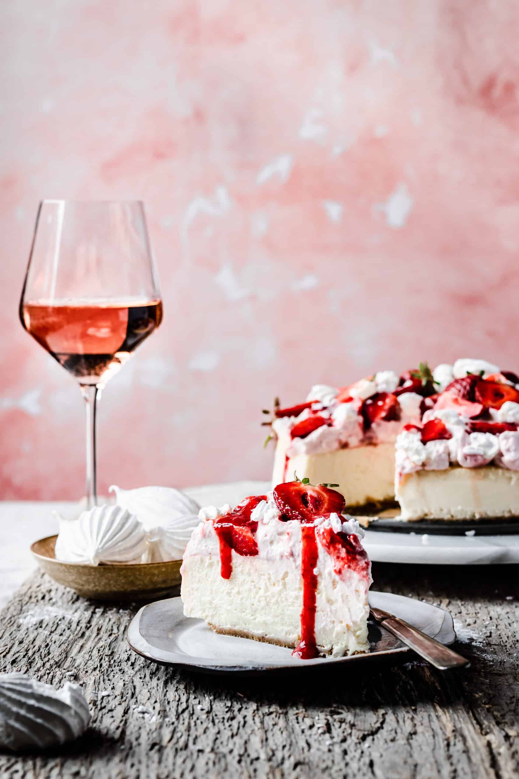 A slice of eton mess cheesecake with strawberry sauce and strawberries on top.