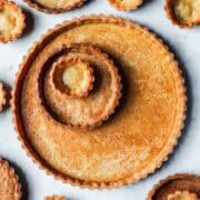 Golden brown baked tart shells in tartlet, mini and large sizes.