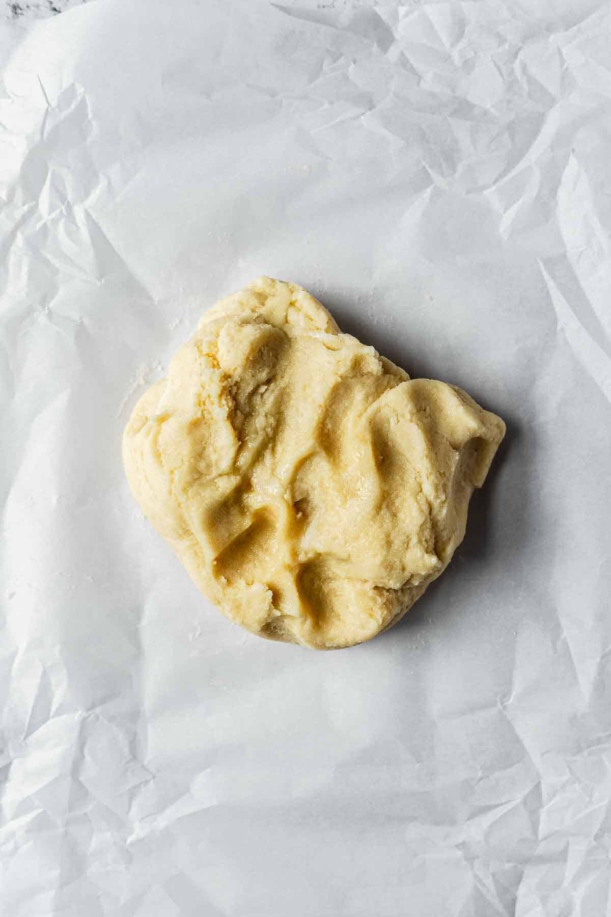 Finished almond paste in a rough ball on parchment paper.