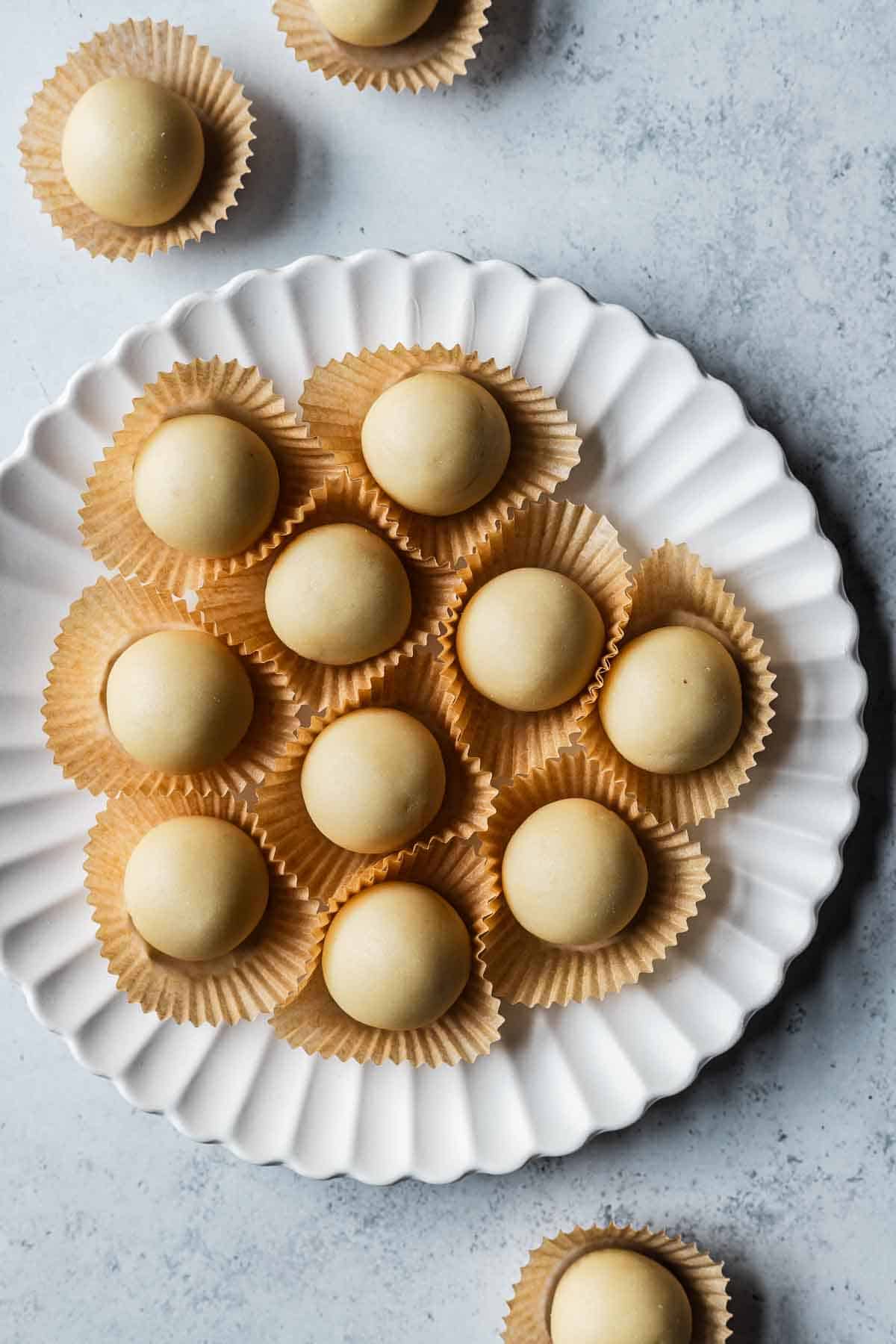 Balls of almond paste in paper candy liners.