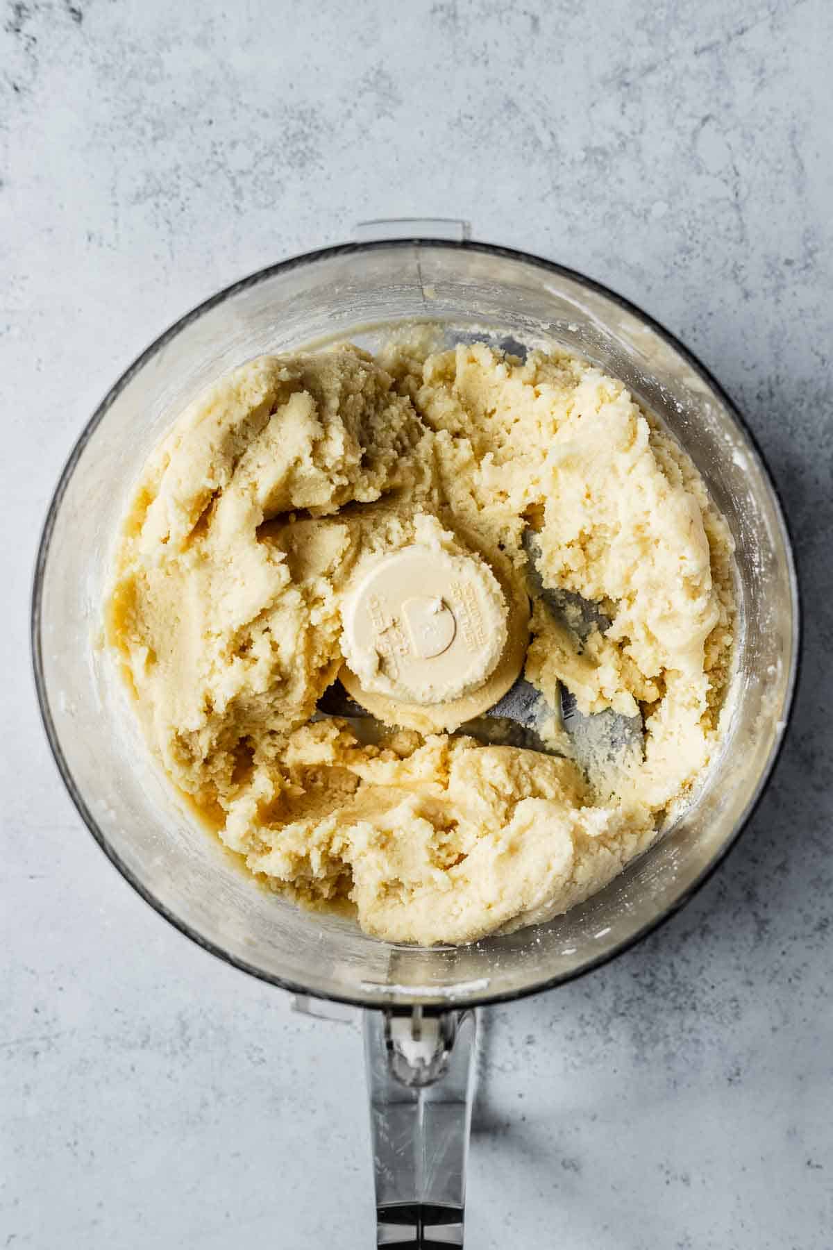 Finished almond dough in bowl of food processor.