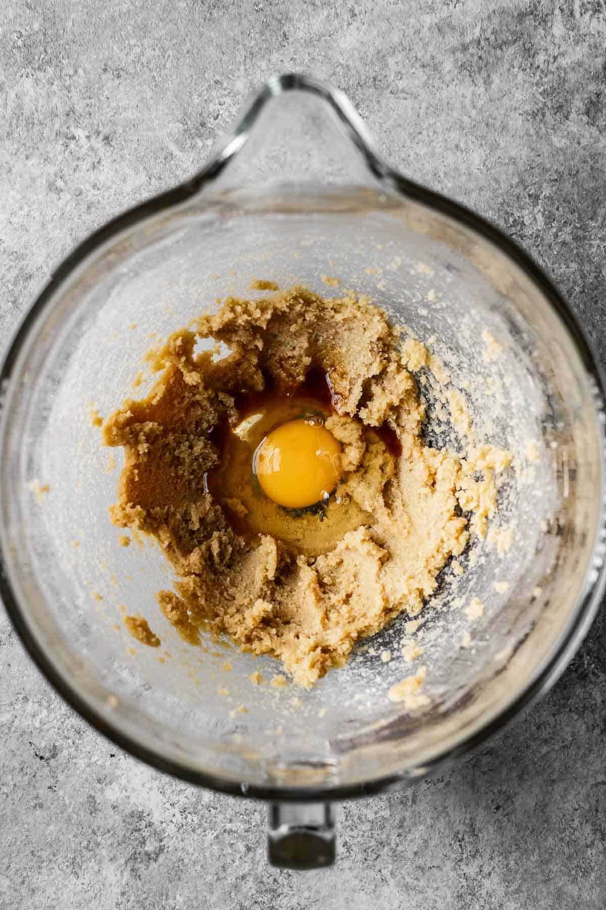 Eggs and vanilla added to creamed butter and sugar in a mixing bowl.