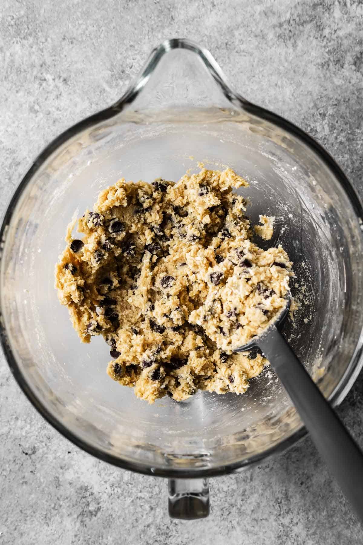 A mixing bowl with fully combined coconut chocolate chip cookie dough.