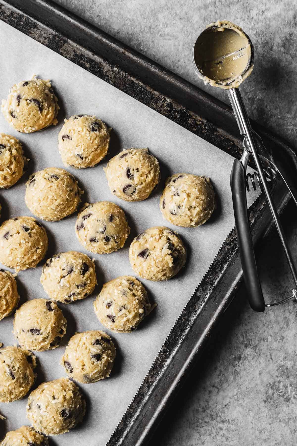Scoops of cookie dough on a parchment lined baking pan.