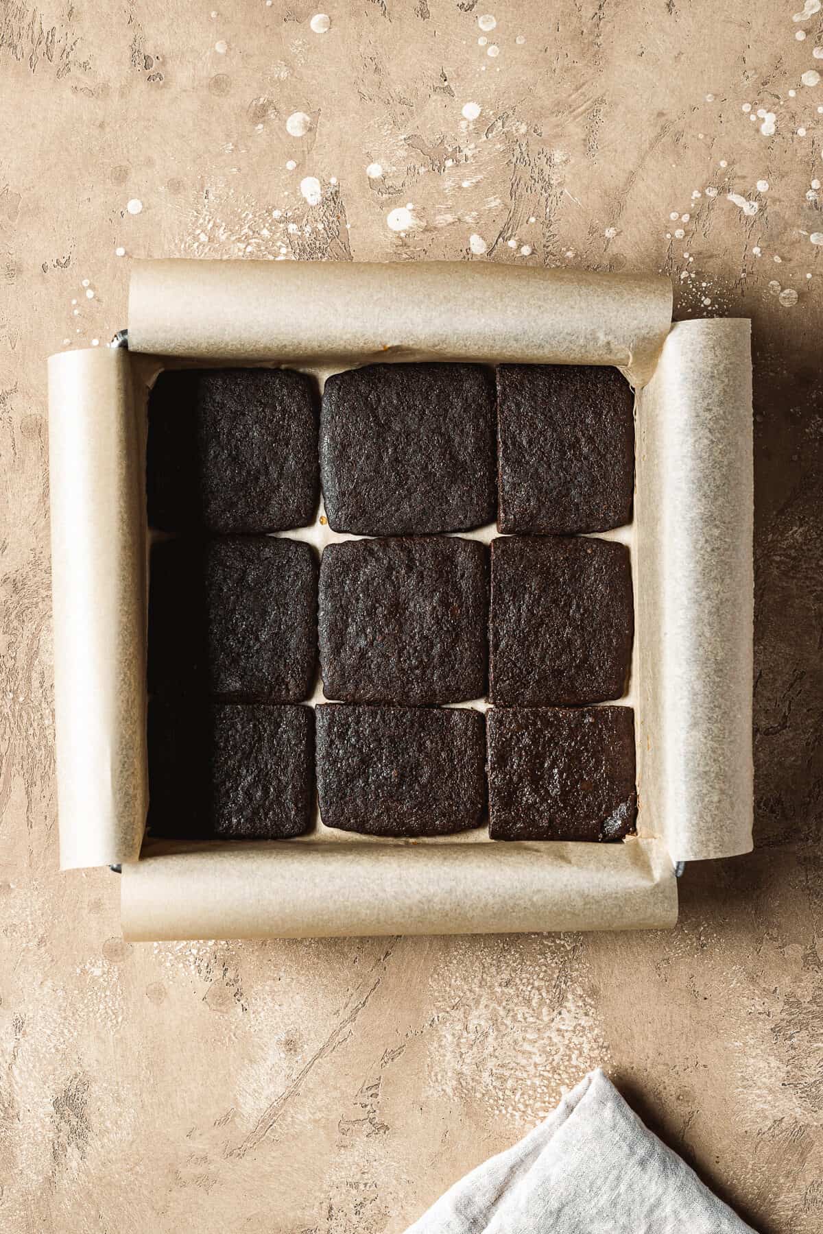 A layer of chocolate wafer cookies in a square pan.