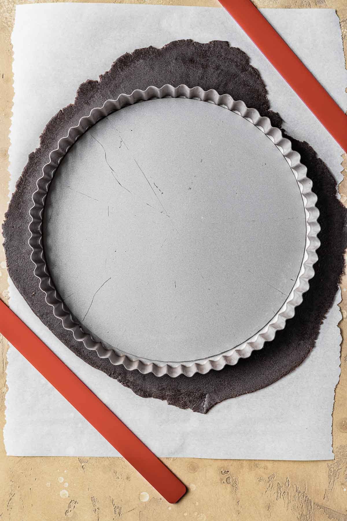 An empty tart pan on top of rolled out dough.