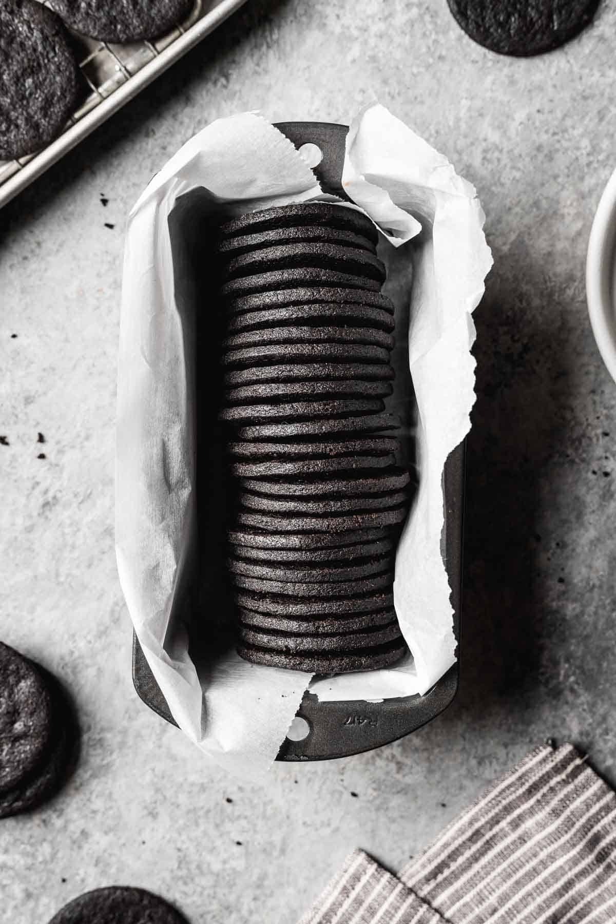 A row of round dark chocolate cookies in a parchment lined pan.