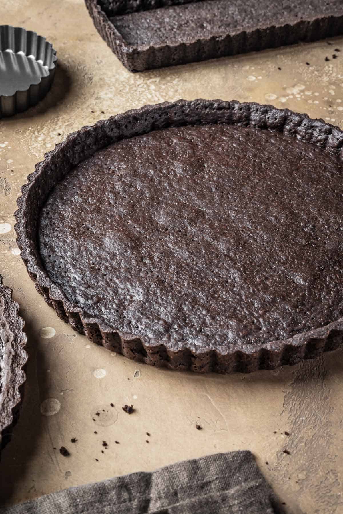 A baked chocolate tart crust with a shiny egg washed interior.