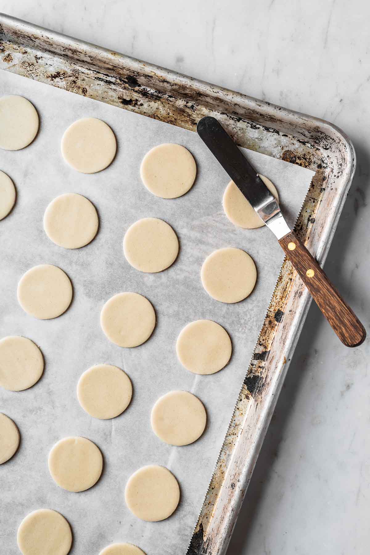 Unbaked vanilla cookies on a parchment lined baking sheet.