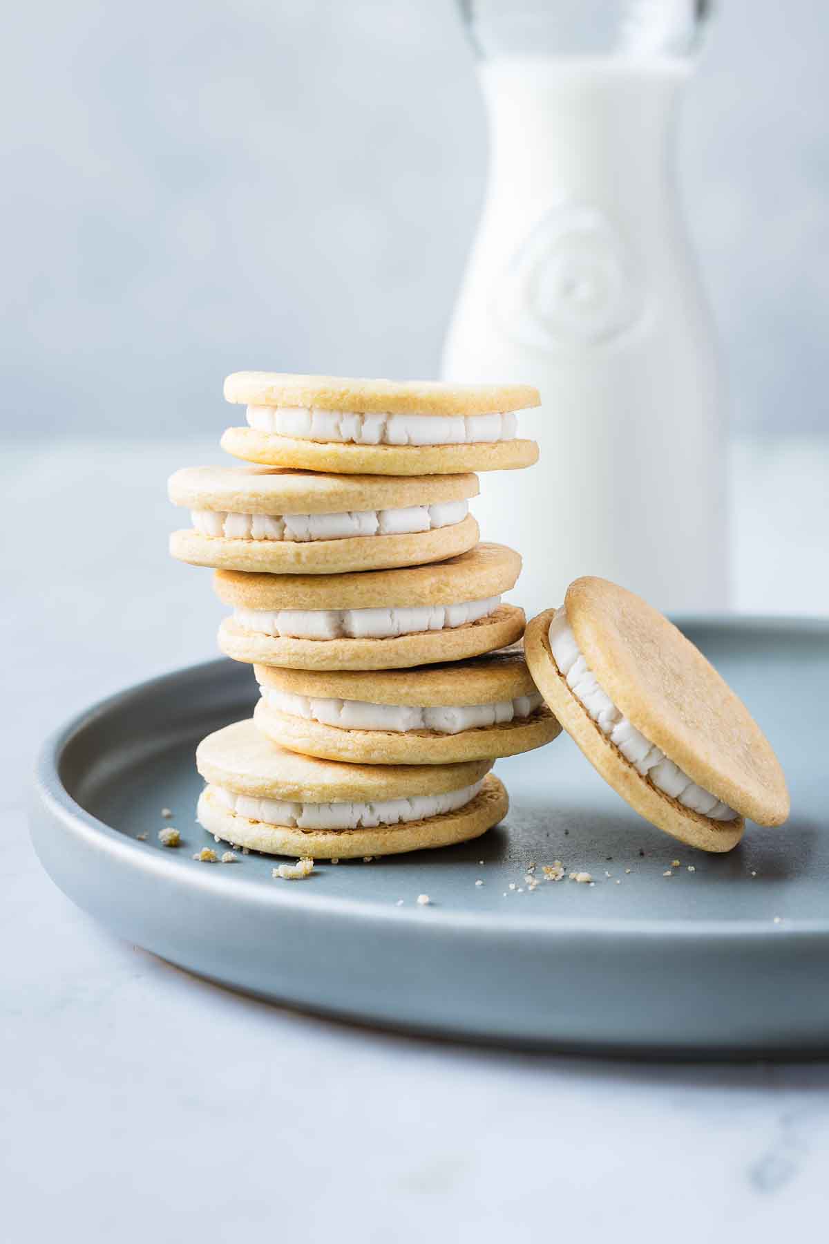 A stack of five Golden Oreo cookies with one leaning at an angle on a blue plate.