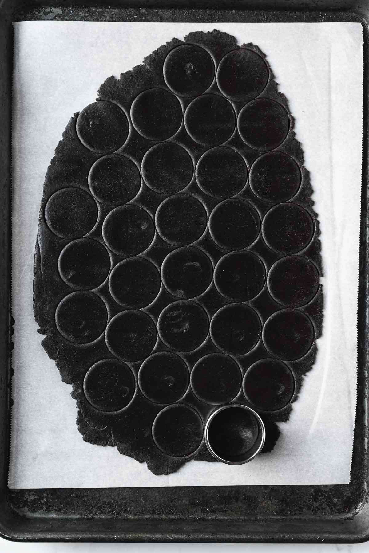 Circular cutouts of chocolate cookie dough on parchment paper.