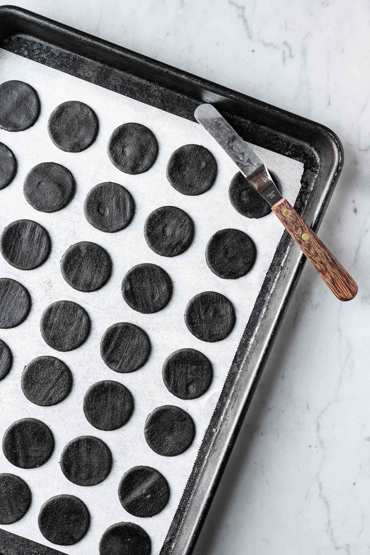 Chocolate cookie dough cutouts on a parchment lined baking sheet.