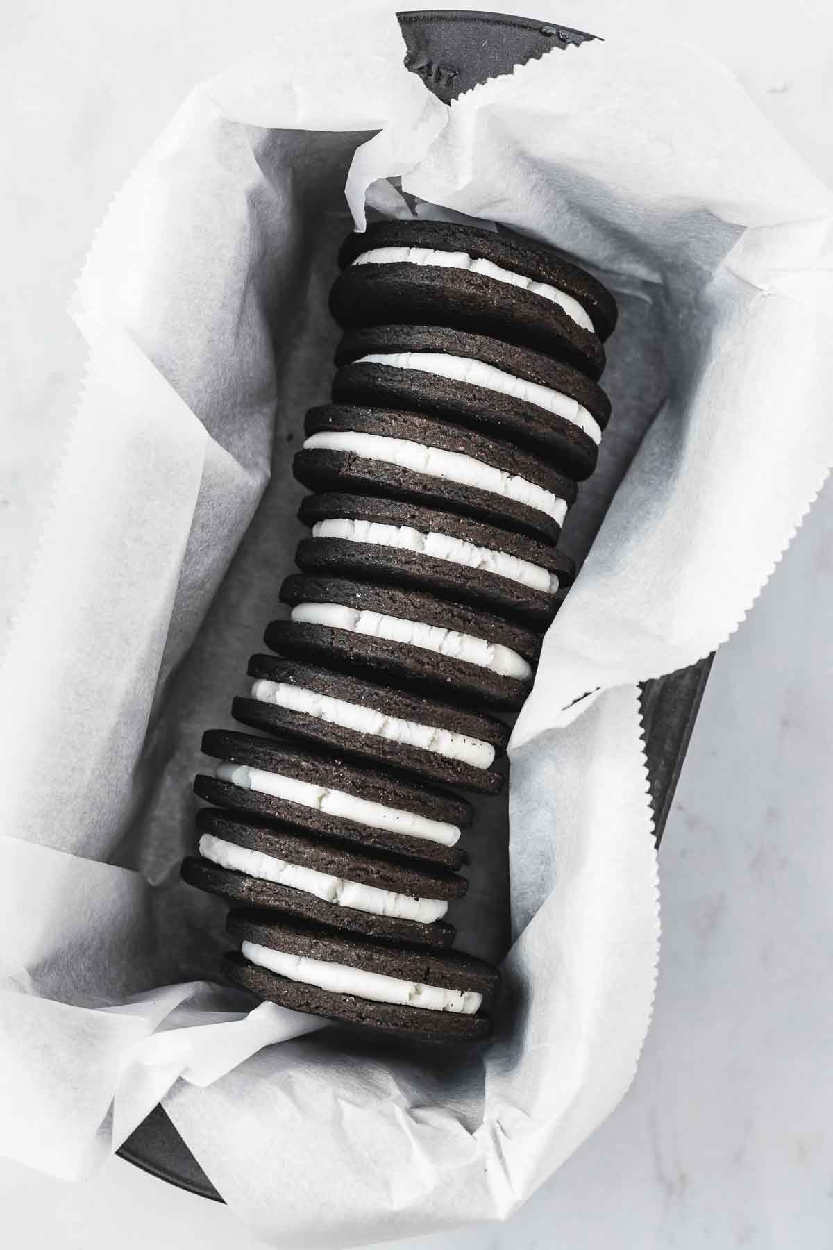 A stack of chocolate sandwich cookies with white filling in a metal pan.