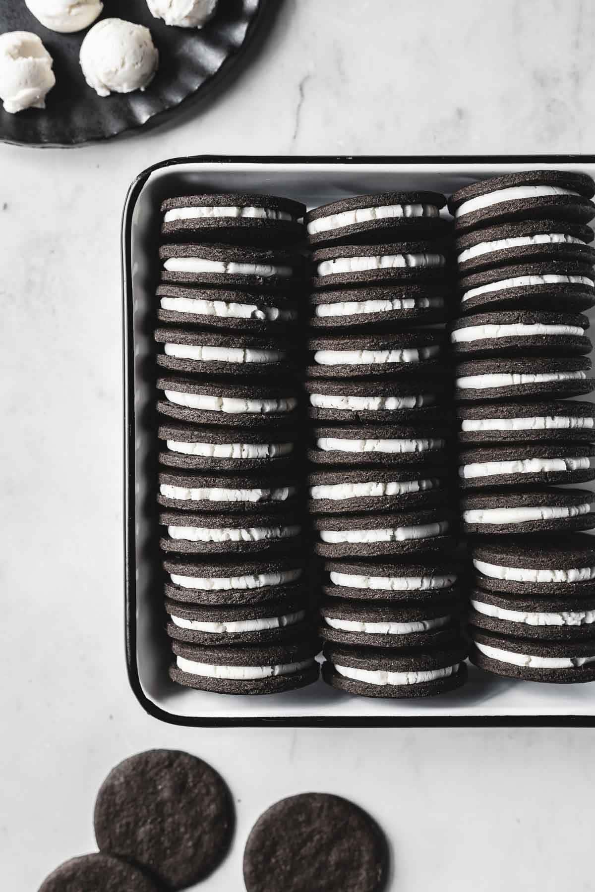 Rows of chocolate sandwich cookies with white creme filling in a pan.